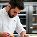 Gourmet chef in a pristine yacht galley preparing a refined dish.